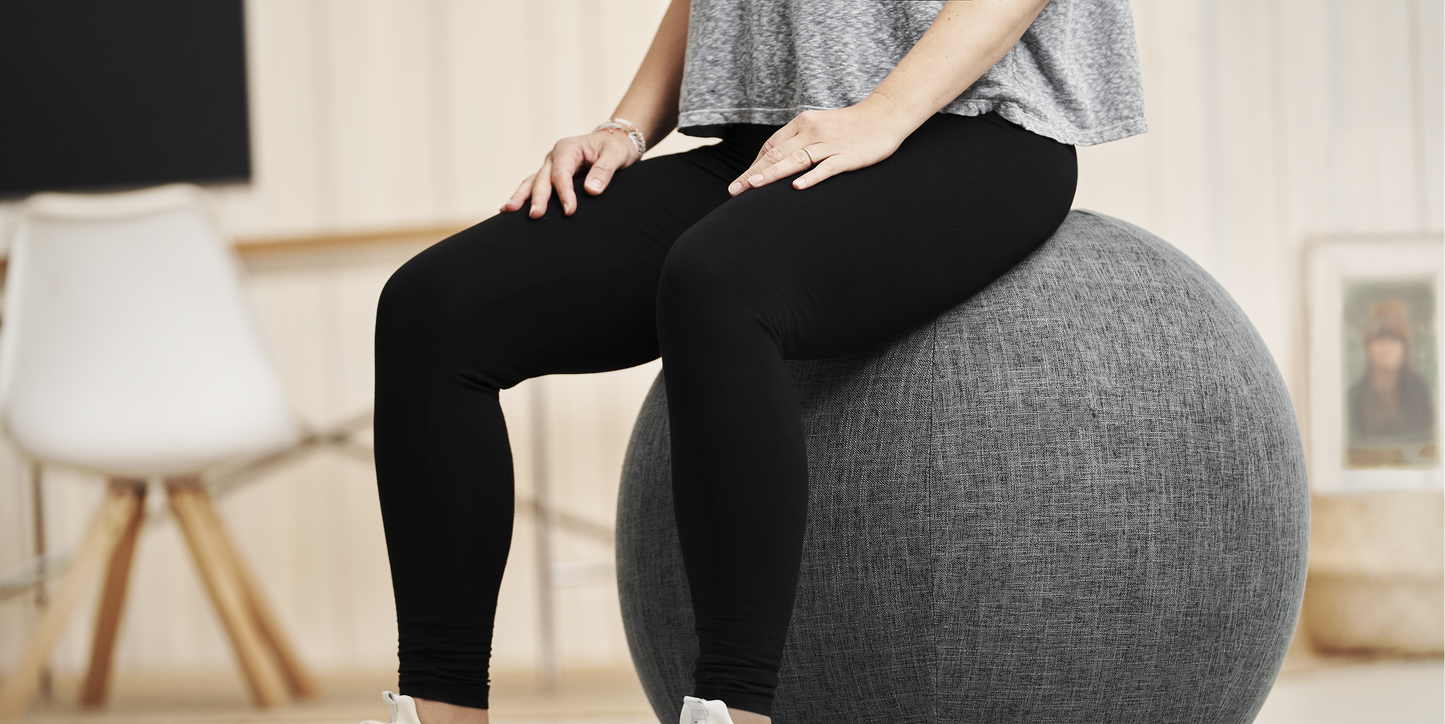 Person sitzt auf dem grauen Treasy Home Office Sitzball mit Stoffbezug – ergonomisches Sitzen für eine aufrechte Haltung