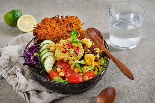 Holzlöffel aus Akazienholz in einer Bowl mit Salat, Kichererbsen und Falafel, daneben ein zweiter Löffel