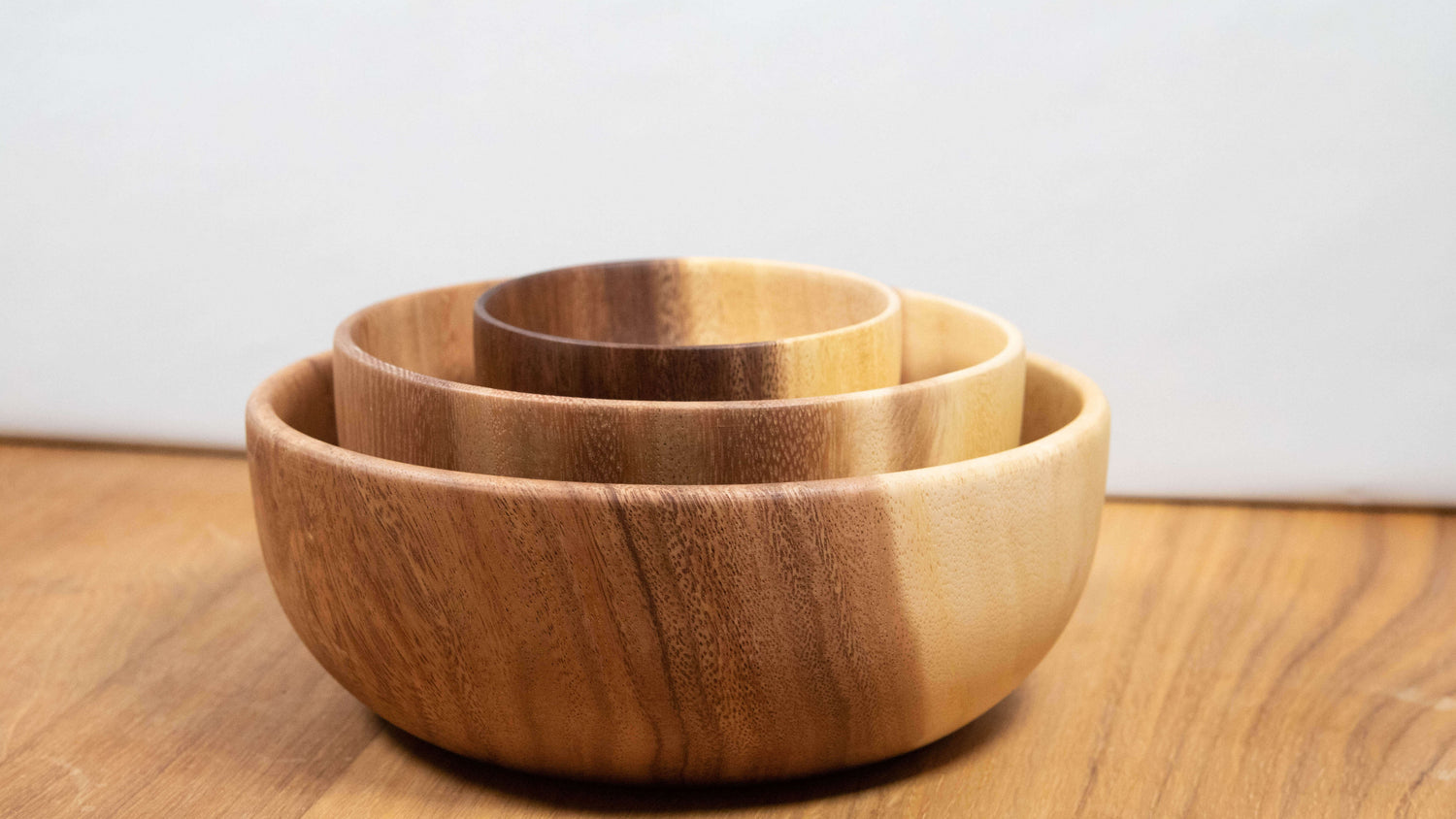 Das Bild zeigt ein Set ineinander stapelbarer Schalen aus Akazienholz, das durch seine sanften Farbverläufe und natürliche Maserung besticht. Jede Schale ist individuell im Ton – von hellbeigem Holz bis zu warmem Karamellbraun – und unterstreicht den handgefertigten Charakter. Die runde, harmonische Form und das glatte Finish machen sie ideal für den täglichen Gebrauch oder als dekoratives Element auf Tisch und Sideboard.