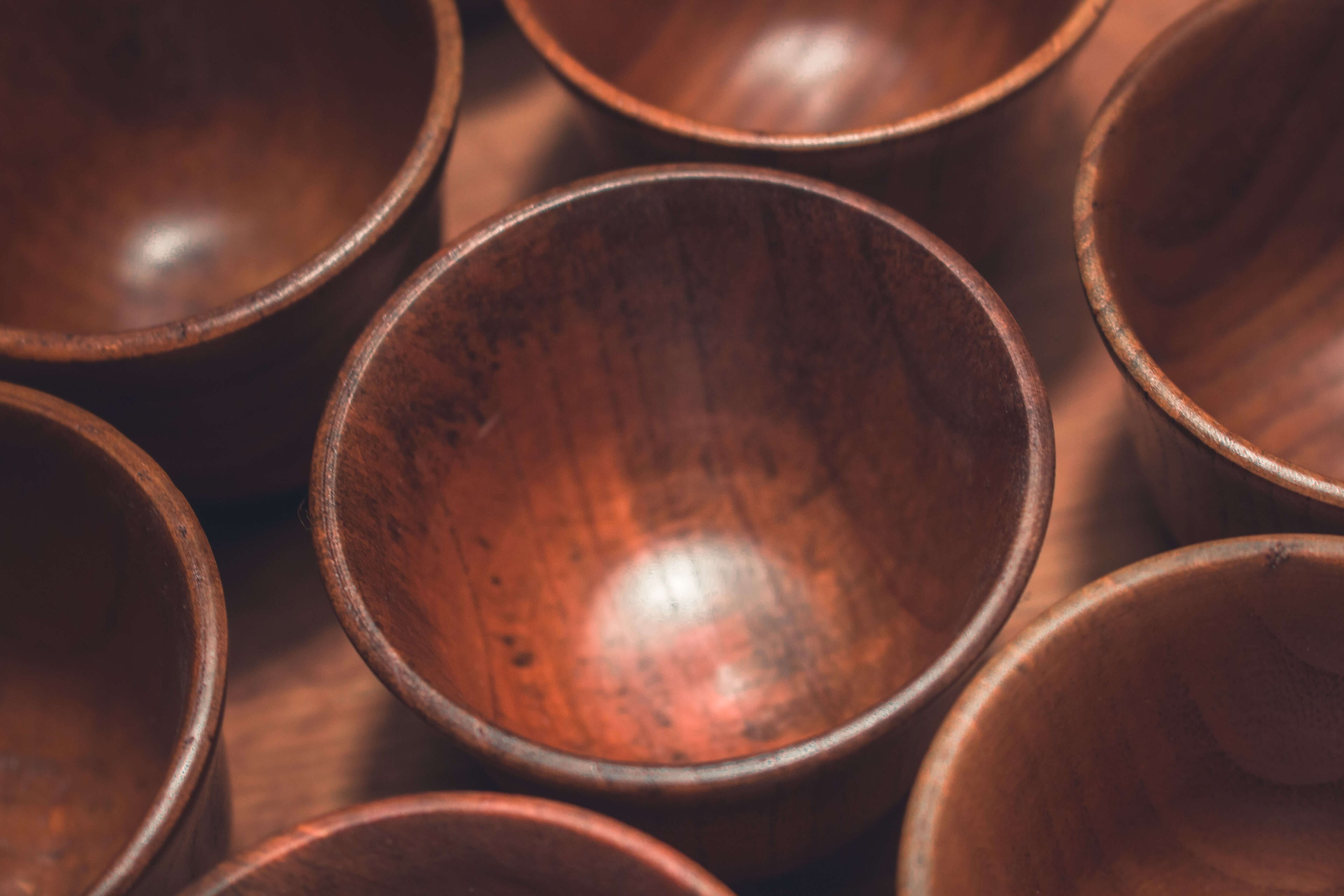Das Bild zeigt mehrere Teebecher aus Jujube-Holz in einer harmonischen Anordnung. Die weiche Beleuchtung betont die handwerkliche Struktur und den natürlichen Glanz des Holzes. Durch die feine Maserung und die leicht unterschiedlichen Farbtöne wirkt jede Tasse individuell und lebendig – perfekt für Teeliebhaber, die Wert auf natürliche Materialien und schlichte Ästhetik legen.