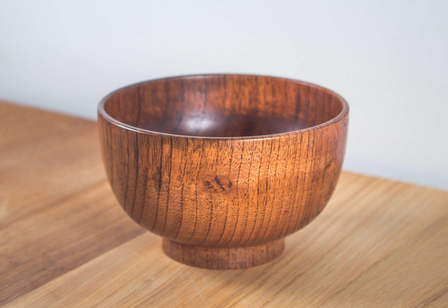 Diese Aufnahme zeigt eine runde Schale aus edlem Jujube-Holz mit feiner, dunkler Maserung und sanftem Glanz. Die kompakte Form mit leicht erhöhtem Fuß ist typisch für traditionelle japanische Servierschalen. Durch ihre warme Farbe und natürliche Struktur eignet sie sich perfekt für Reis, Miso-Suppe oder Snacks – ebenso als stilvolles Element in einer minimalistischen Tischdekoration.