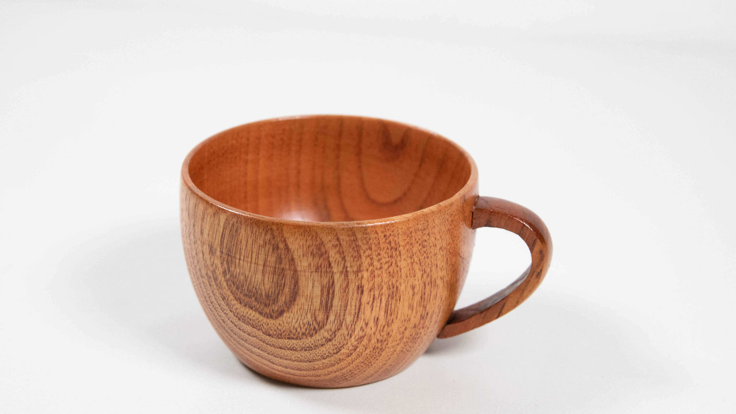 Nahaufnahme einer handgefertigten Teetasse aus Jujube-Holz mit feiner Maserung und elegant geschwungenem Henkel auf weißem Hintergrund.