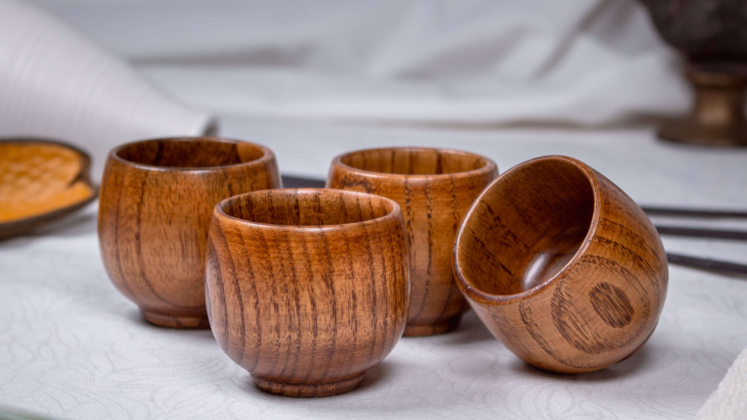 Das Foto zeigt vier Teeschälchen aus Jujube-Holz, elegant arrangiert in warmer, natürlicher Umgebung. Das fein gemaserte Holz mit seinem sanften Glanz und den lebendigen Farbverläufen unterstreicht den handgefertigten Charakter der Schälchen. Durch ihre runde, kompakte Form liegen sie angenehm in der Hand – ideal für Teezeremonien, kleine Snacks oder Desserts. Jedes Stück ist ein Unikat und verbindet traditionelle Handwerkskunst mit modernem, minimalistischen Design.