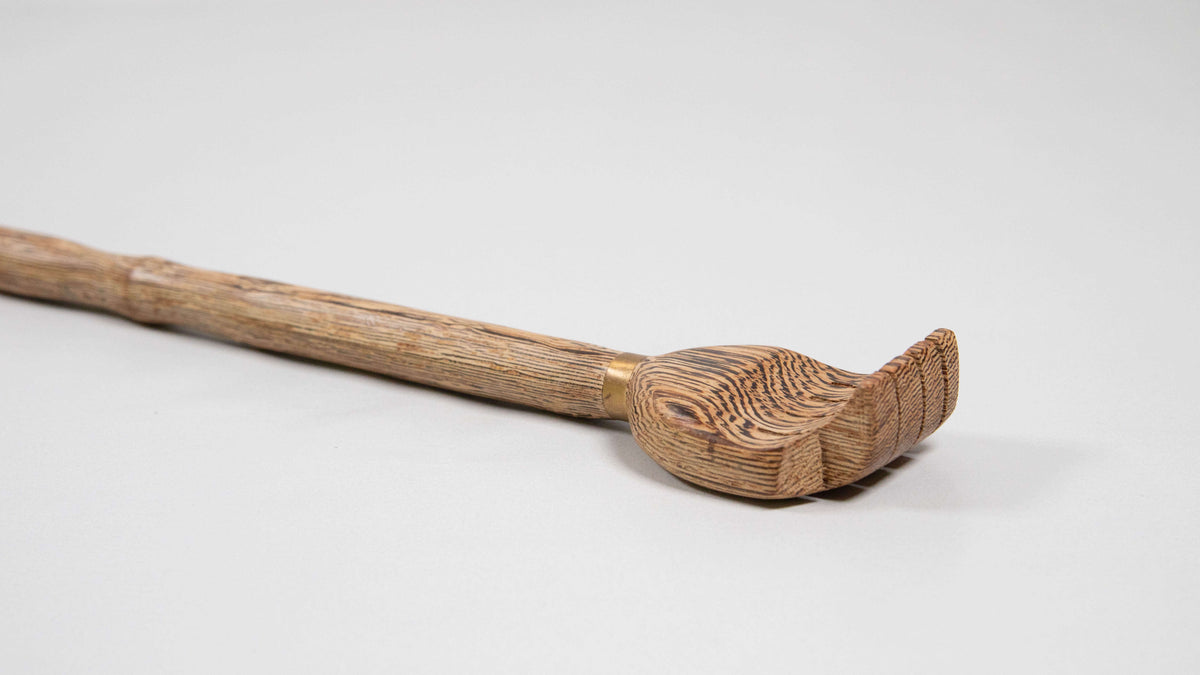 Nahaufnahme des handförmigen Kopfs eines Rückenkratzers aus Holz mit Messingring am Griff